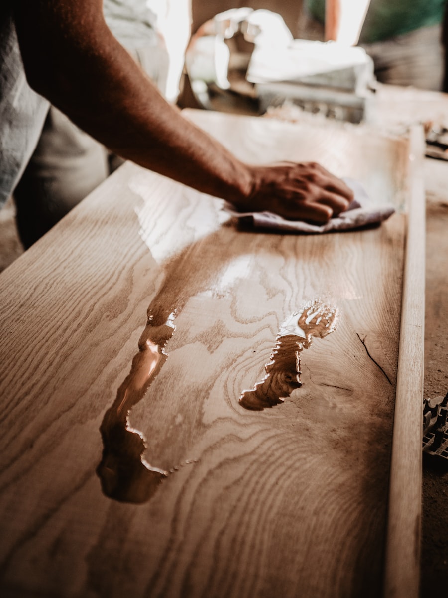 A hand oiling a freshly sanded wooden tabletop